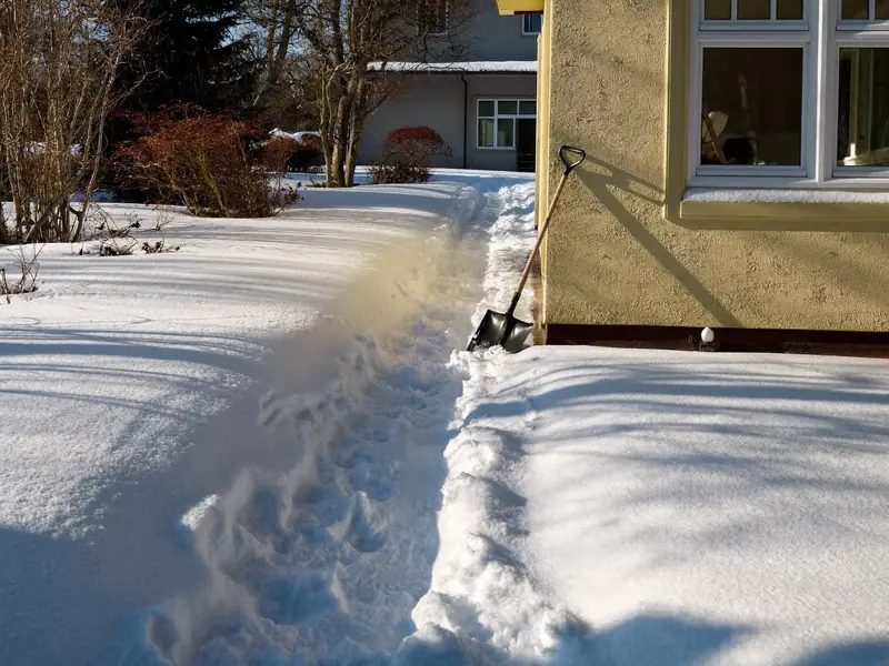 Geräumter Gehweg nach Schneefall vor einem Haus