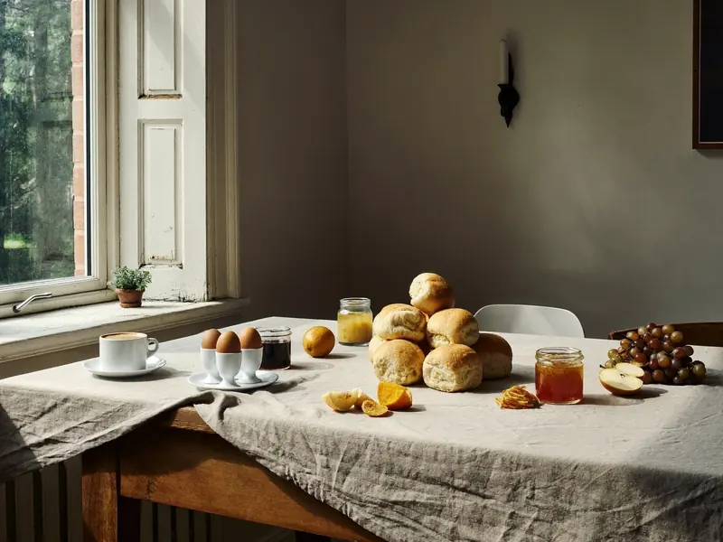 Gedeckter Frühstückstisch mit Brötchen, Eiern und Marmelade