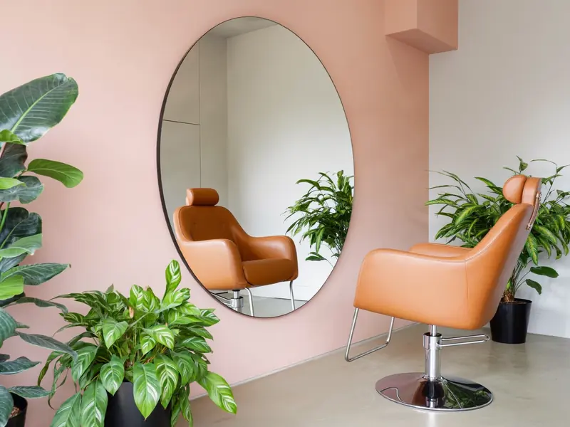 Heller Salon mit rundem Spiegel und zwei Stylingstühlen