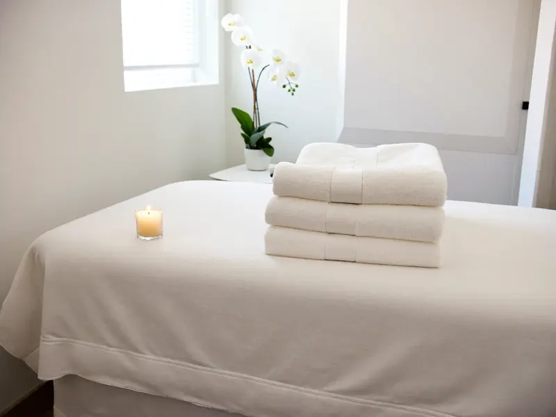 Ruhiger Behandlungsraum mit Liege, Handtüchern und Orchidee