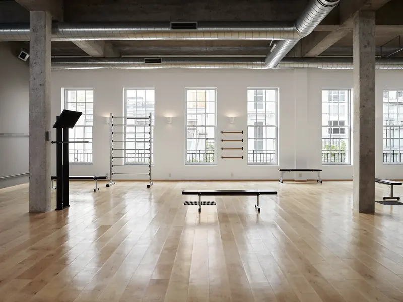Heller Trainingsraum mit Holzboden und großen Fenstern