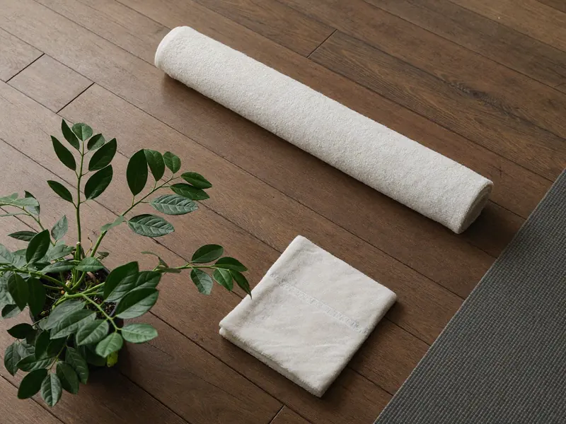 Yogamatte, Handtuch und Pflanze auf Holzboden